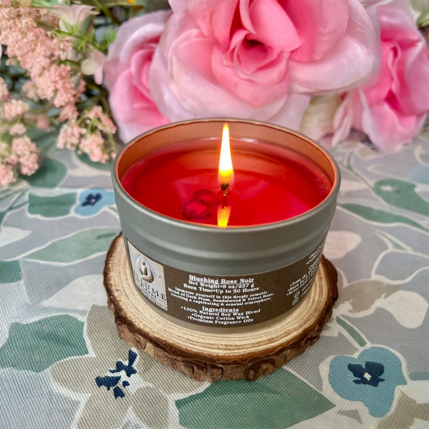 Blushing Rose Noir candle styled on wooden coaster with florals, creating an elegant romantic ambiance